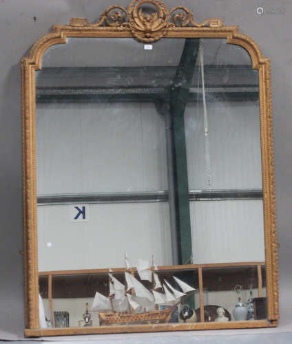 A late Victorian gilt composition overmantel mirror of arched form, the flowerhead and ribbon