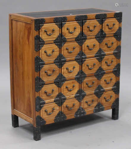 A 20th century Chinese softwood bank of twenty drawers with brass strapwork decoration, on block