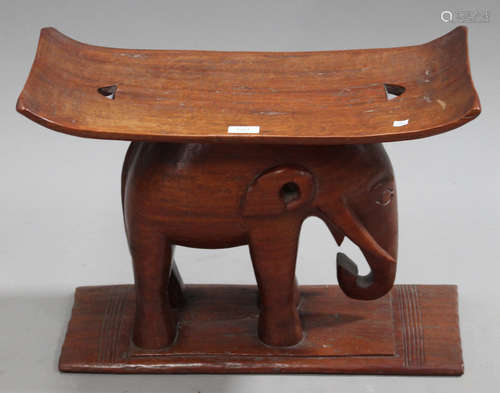 A 20th century African carved hardwood stool with elephant supports, width 59cm.Buyer’s Premium 29.