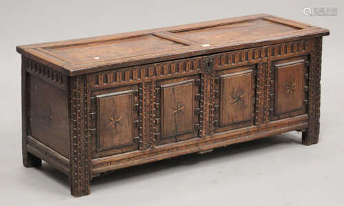 A late 17th century oak coffer, the hinged lid above an inlaid panel front, on stile supports,