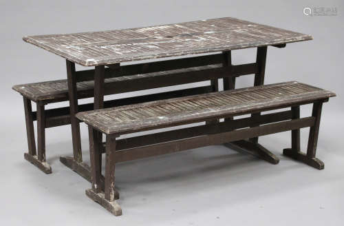 A 20th century slatted teak garden table, length 143cm, and two matching benches.Buyer’s Premium