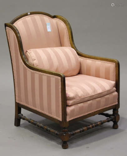 A George V mahogany armchair with arched back, upholstered in a pink stripped fabric, on turned