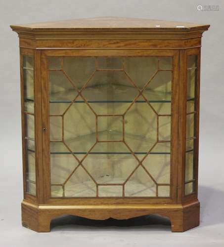 An Edwardian satinwood corner display cabinet with crossbanded borders, the moulded pediment above