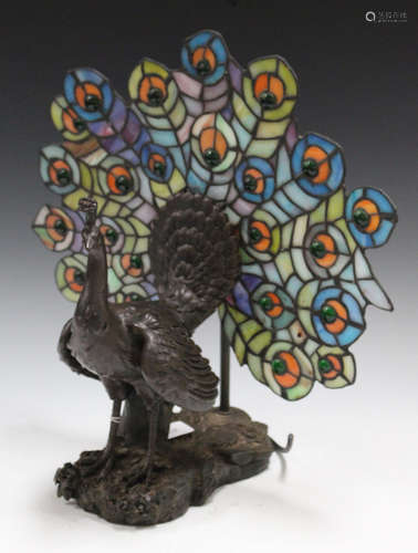 A late 20th century Tiffany style bronzed and stained glass table lamp in the form of a peacock,