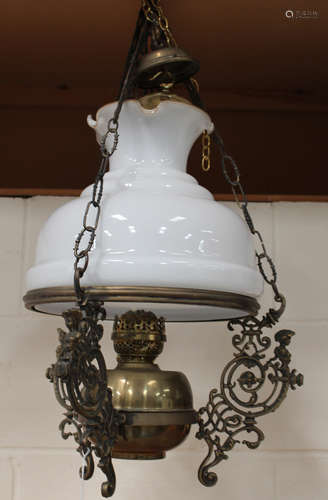 An early 20th century gilt brass hanging oil lamp, fitted with a frilly opaline glass shade,