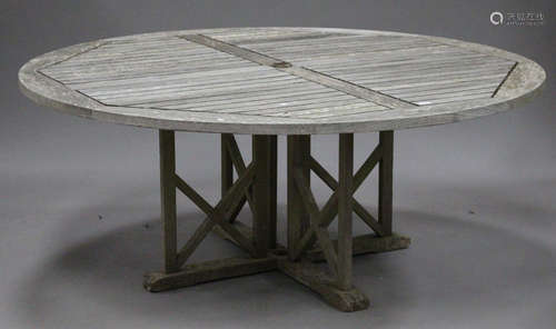 A large late 20th century teak slatted garden table, the circular top above 'X' framed supports,