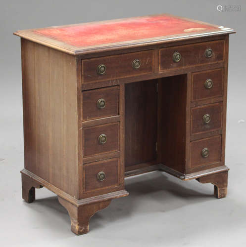 A 20th century reproduction mahogany kneehole desk, fitted with eight drawers and a cupboard, on