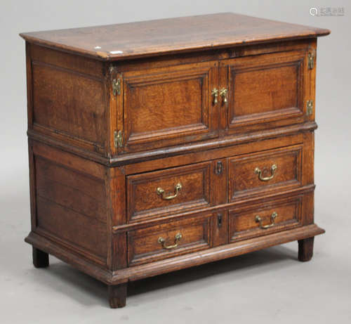 A 17th century provincial oak chest, the hinged lid above a pair of panel doors and two drawers,