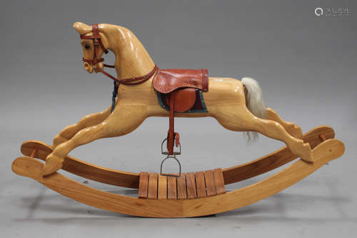 A modern carved oak rocking horse with brown leather saddle, height 91cm, length 159cm.Buyer’s