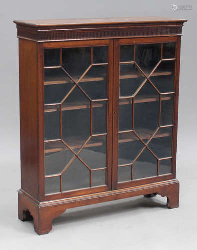 A George V mahogany bookcase, the stop fluted frieze above a pair of astragal glazed doors, on