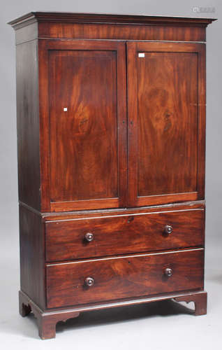 A George III mahogany linen press, the moulded pediment above a pair of panel doors revealing