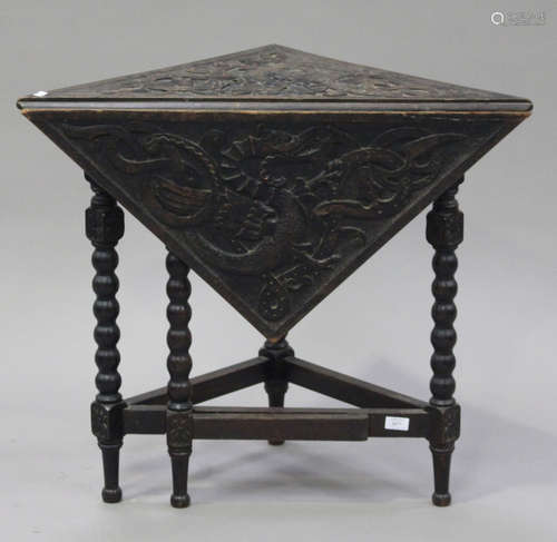 A George V oak gateleg corner table, the hinged top carved with dragons, raised on turned legs,