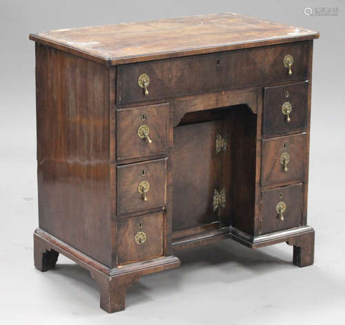 A 20th century reproduction walnut kneehole desk, fitted with seven drawers and a cupboard, on