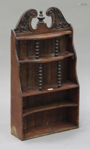 A late 19th century walnut wall shelf with a carved foliate crest and turned spindle supports,