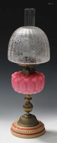 A late Victorian pink glass and brass mounted table oil lamp with an acid etched shade, the