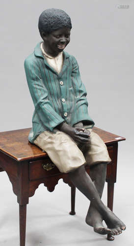 A modern cast composition figure of a seated boy wearing a green blazer and shorts, height 110cm.