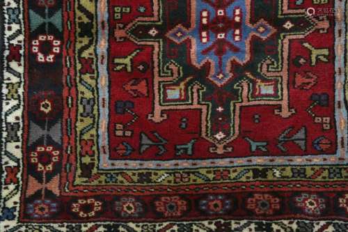 A VERY LONG HERIZ RUNNER, NORTH-WEST PERSIA approx: 24ft.3in. x 2ft.9in.(739cm. x 84cm.) The field with single row of 15 hooked floral medallions surrounded by small angular motifs. In linked rosette and leaf vine border between floral stripes. This runner has full pile. Ends and selvages original. In general this runner is in very good condition throughout . Very good size, long and narrow. Popular type. Mid 20th century