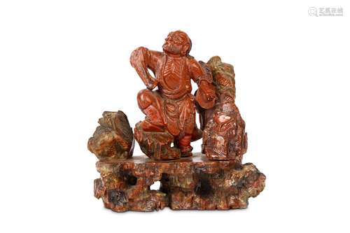 A CHINESE SOAPSTONE CARVING OF A SEATED FIGURE. Qing Dynasty, 19th Century. Seated on a rocky base