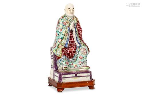 A CHINESE FAMILLE ROSE FIGURE. Qing Dynasty. Seated with in long flowing robes on a throne the