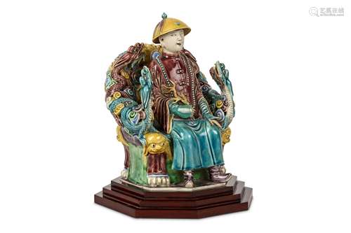 A CHINESE TURQUOISE AND AUBERGINE GLAZED FIGURE. Qing Dynasty. Seated on an elaborate dragon throne