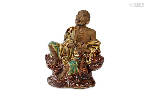 A CHINESE GLAZED SHIWAN FIGURE OF A LOHAN. Qing Dynasty, 19th Century. Seated on a rocky base, in