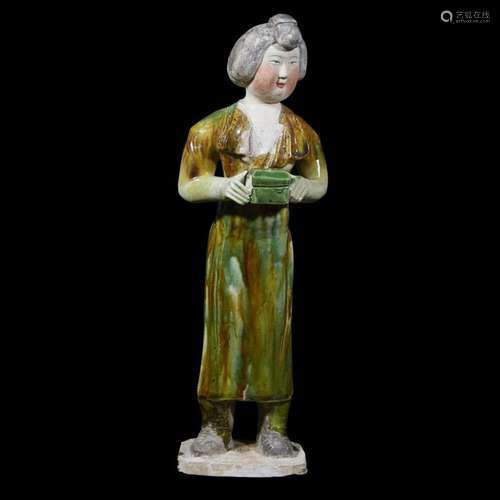 A Chinese sancai-glazed pottery figure of a standing attendant bearing a small coffer, tang dynasty, 8th century