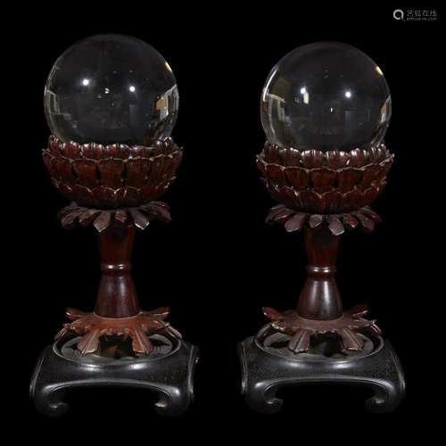 A pair of Chinese rock crystal spheres, on carved hardwood stands, the spheres late qing dynasty