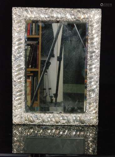 An early 20th Century hallmarked framed silver rectangular bevel glass mirror with ribbed and foliate scroll detail to frame