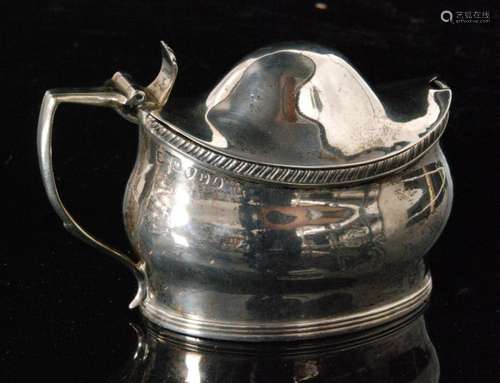 A George III hallmarked silver boat shaped mustard pot and cover with reeded and gadroon borders terminating in scroll handle