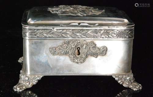 An early 20th Century continental white metal cushioned rectangular casket raised on four scroll feet with floral spray to hinged cover above leaf and berry frieze