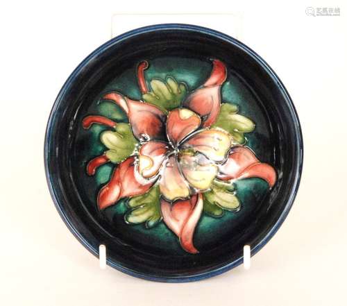 A Moorcroft footed bowl decorated in the Columbine pattern with a central tubelined flower against a blue wash ground