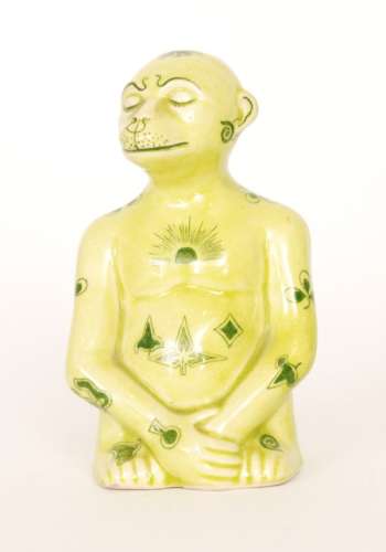 An early 20th Century model of a seated mythical monkey type creature glazed in yellow with green transfer applied motifs