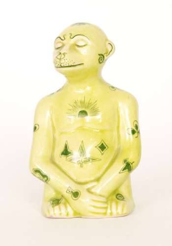 An early 20th Century model of a seated mythical monkey type creature glazed in yellow with green transfer applied motifs