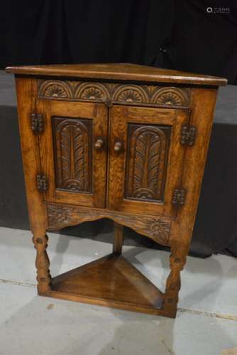 A carved oak floorstanding corner cupboard in the 19th Century style