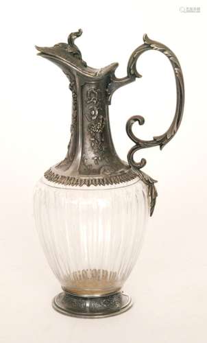 A W.M.F pewter mounted glass claret jug with acanthus scroll handle embossed with musical instruments on a circular base