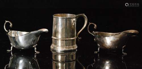 A pair of hallmarked silver sauce boats each raised on three pad feet and terminating in flying scroll handles