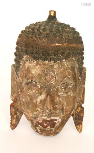 A carved wooden face mask of a Buddha