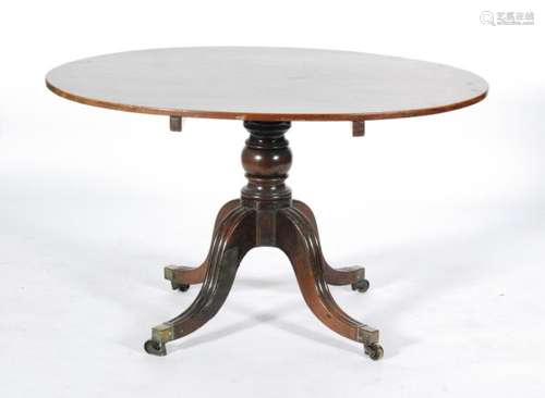 A 19th Century oval mahogany pedestal dining table on splayed legs terminating in brass feet