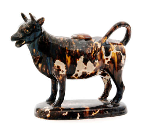 A late 18th Century Staffordshire Neale Pottery cow creamer and cover decorated in an all over treacle glaze