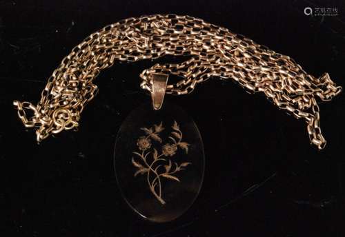 An early 20th Century oval tortoiseshell pique work pendant decorated with a floral spray