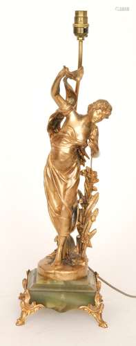 An Art Nouveau gilt lamp of a standing lady holding a flower in one hand