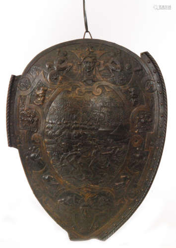 A late 19th Century oval ceremonial shield embossed and chased on gilt metal depicting a battle scene with soldiers on horseback in combat outside a besieged citadel and camp