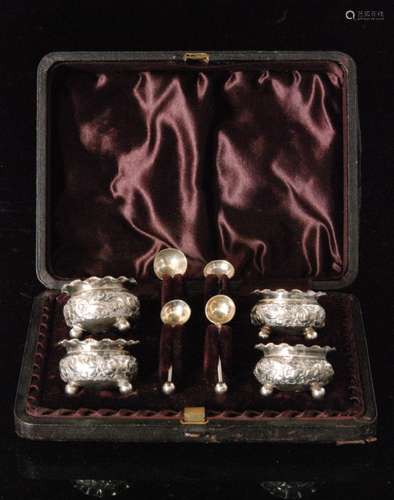 A cased set of four Victorian hallmarked silver cauldron salts each with embossed foliate decoration and raised on three ball feet