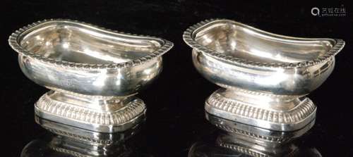 A pair of George IV hallmarked silver boat shaped open pedestal salts of plain for with gadroon borders