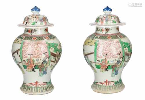 A pair of Famille Verte porcelain lidded baluster vases decorated with figures in a garden.