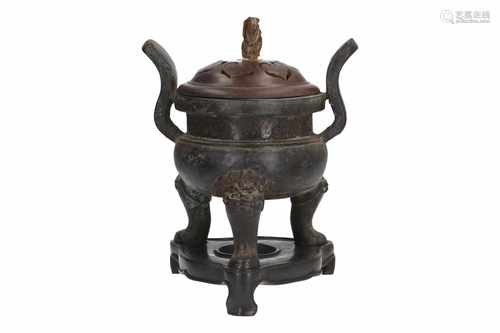 A bronze censer with wooden lid and jade knob, on wooden stand. The three legs in the shape of