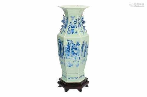 A hexagonal blue and white porcelain vase on wooden base, decorated with figures bringing gifts.