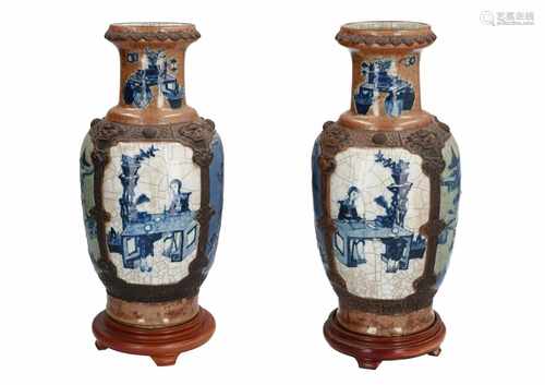 A pair of polychrome porcelain vases on wooden base, decorated with figures, animals and landscapes.