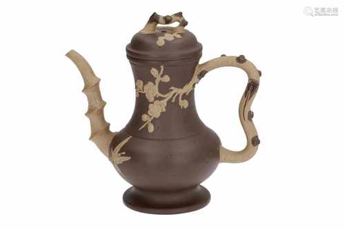 A Yixing teapot with relief decor of flowers and the knob and handle in the shape of branches.