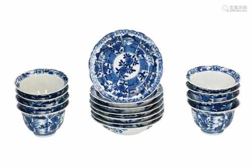 A set of eight blue and white porcelain cups with seven saucers, decorated with flowers. Marked with